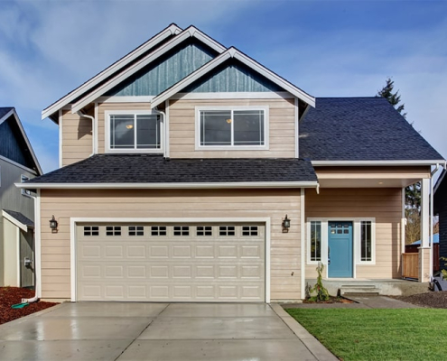 A two-story house featuring a garage and a spacious driveway.