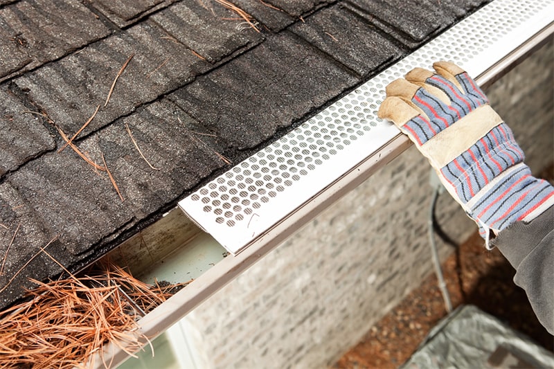 A person installing a gutter using a tool, demonstrating home maintenance and improvement skills